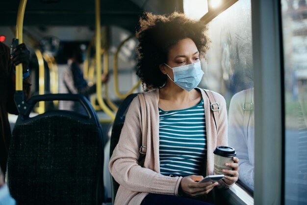 Verstörte afroamerikanische Frau mit Gesichtsmaske während der Fahrt mit öffentlichen Verkehrsmitteln