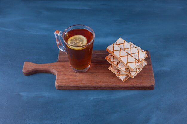 Verstreute Waffelkekse mit einer Tasse Kräutertee.