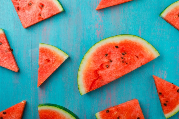 Verstreute Wassermelonenstücke auf blauem Hintergrund, Draufsicht.