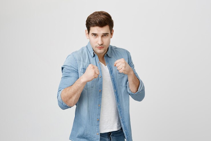 Kostenlose Foto verteidigungs- und schutzkonzept starker mann mit jeanshemd und stylischem haarschnitt, der ernsthaft und selbstbewusst aussieht und die fäuste geballt hält, um sich vor beleidigungen und schlechter behandlung zu verteidigen