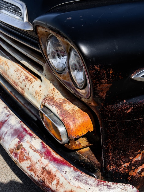 Kostenloses Foto vertikal von den scheinwerfern und der stoßstange eines alten rostschwarzen autos
