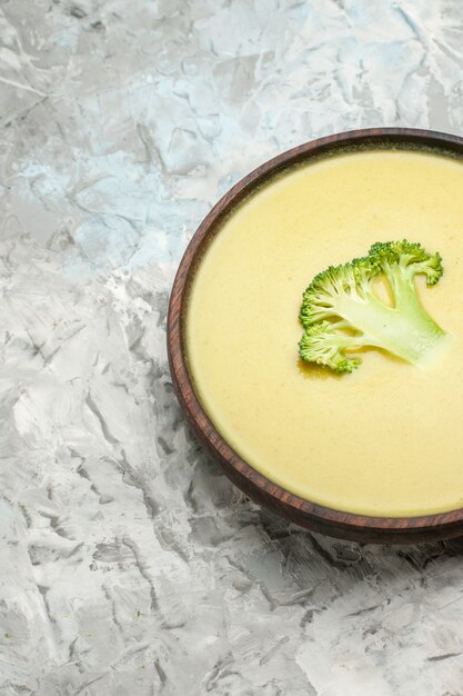 Vertikale ansicht der cremigen brokkolisuppe in einer braunen schüssel auf grauem hintergrund