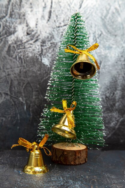 Vertikale Ansicht der goldenen Ringglocke, die an der Kiefer für Weihnachtsfeiertage auf grauem Hintergrund hängt