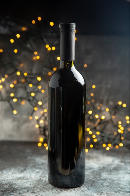 Vertikale Ansicht der roten Glasweinflasche zum Feiern auf dunklem Tisch