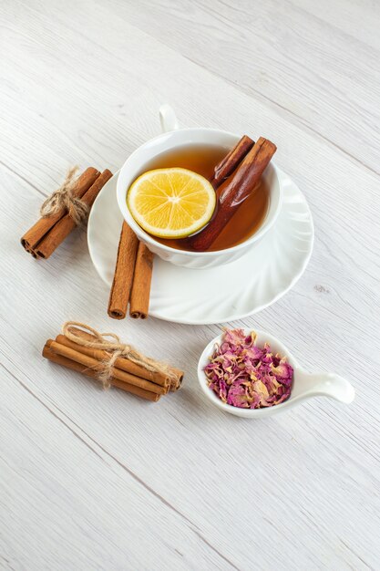 Vertikale Ansicht der Teepause mit Zimt-Limette und Zitrone in einer Tasse auf weißem Hintergrund