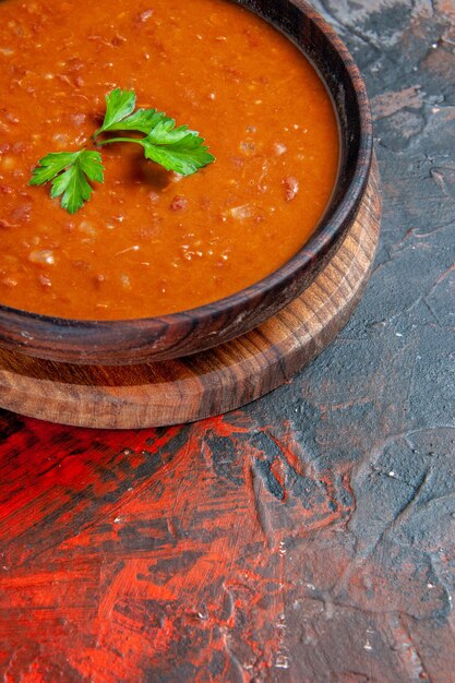 Vertikale Ansicht der Tomatensuppe auf einem braunen Schneidebrett auf einer gemischten Farbtabelle