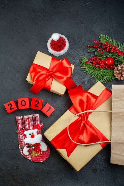 Vertikale Ansicht der Weihnachtsstimmung mit schönen Geschenken mit rotem Band und Zahlen Weihnachtsmannhut-Weihnachtssocke auf dunklem Hintergrund