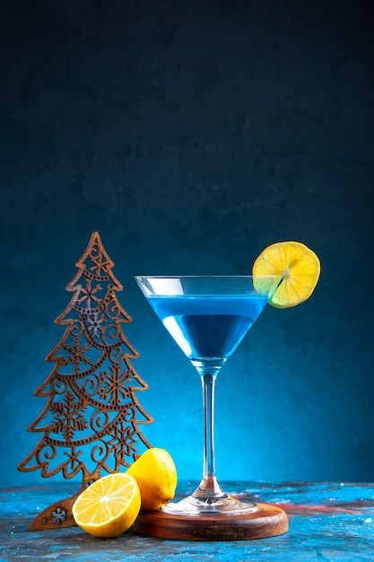 Vertikale ansicht des alchocol-cocktails in einem glasbecher, serviert mit zitronenscheibe und weihnachtsbaum auf blauem hintergrund