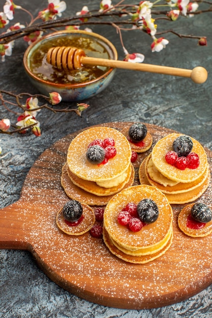 Vertikale Ansicht des klassischen amerikanischen Pfannkuchenhonigs in einer Schüssel auf Grau