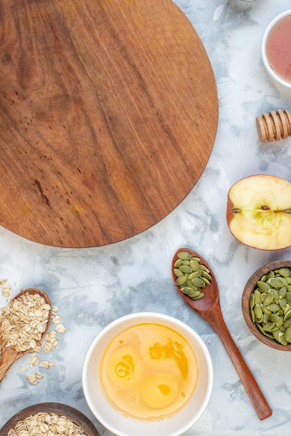 Vertikale Ansicht des runden Holzbretts und der Zutaten für das gesunde Essen auf weißem Hintergrund