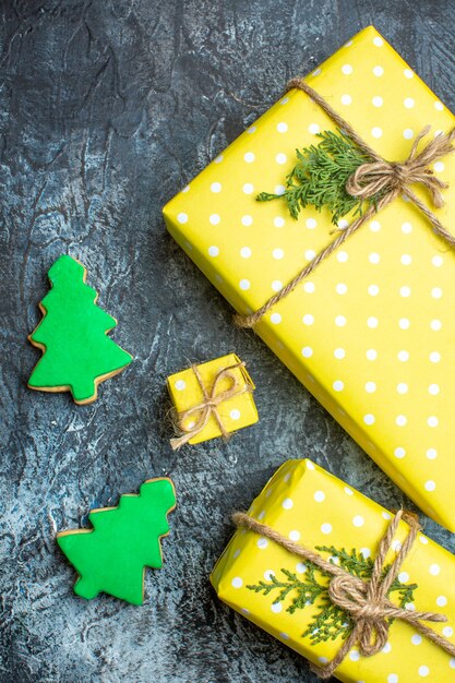 Vertikale Ansicht des Weihnachtshintergrundes mit gelben Geschenkboxen und Keksen auf dunklem Hintergrund