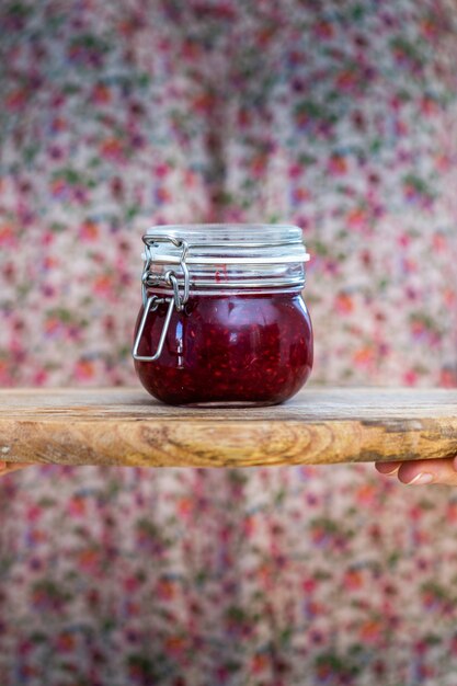 Vertikale Ansicht einer hausgemachten veganen rohen Himbeermarmelade in einem Glas auf einer Holzoberfläche