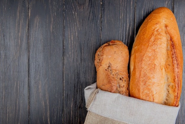 Vertikale Ansicht von Baguettes als Schwarz und Vietnamesisch im Sack auf hölzernem Hintergrund mit Kopienraum