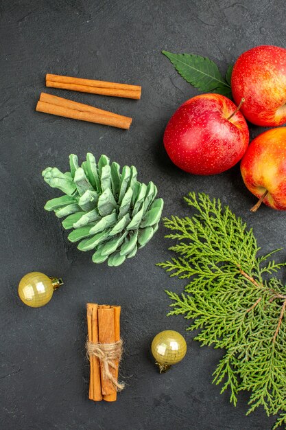 Vertikale Ansicht von frischen Äpfeln-Zimt-Limonen und Dekorationszubehör auf schwarzem Hintergrund