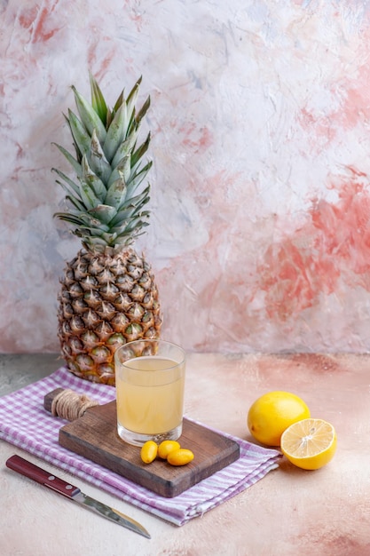 Vertikale Ansicht von Fruchtsaft und Kumquats auf Holzschneidebrett auf lila abgestreiftem Handtuch ganz geschnittene Zitronen und Grapefruit auf pastellfarbenem Hintergrund