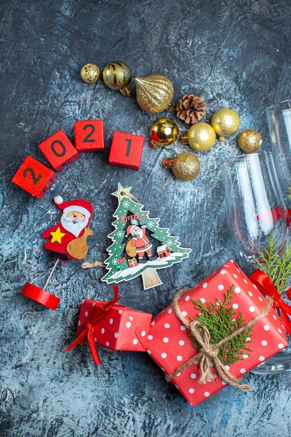 Vertikale Ansicht von gefallenen Glaskelchen und Besteckset Dekorationszubehör Geschenkbox und Weihnachtssockennummern auf dunklem Tisch