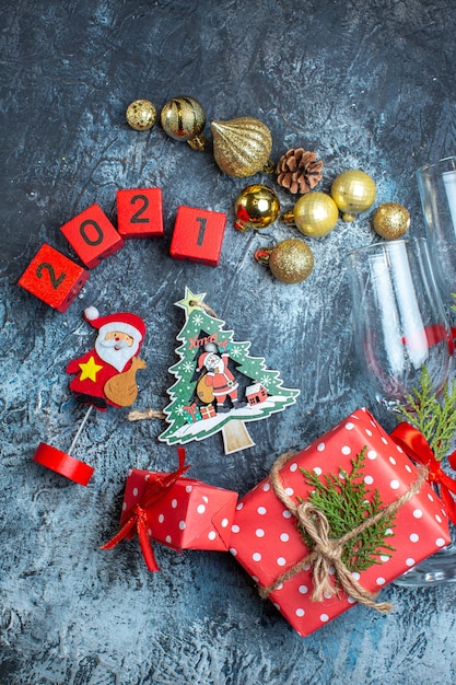 Vertikale Ansicht von gefallenen Glaskelchen und Besteckset Dekorationszubehör Geschenkbox und Weihnachtssockennummern auf dunklem Tisch