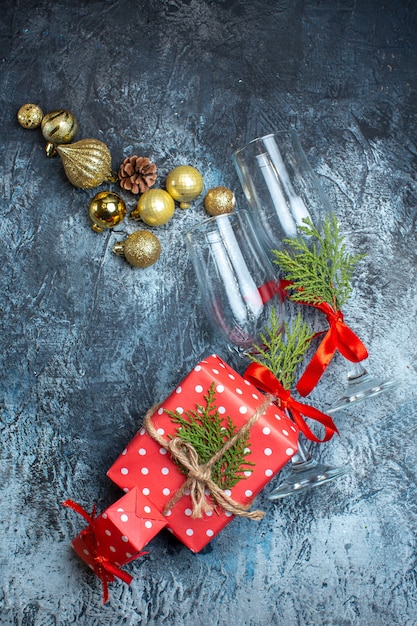 Kostenloses Foto vertikale ansicht von gefallenen glaskelchen und roten geschenkboxen und dekorationszubehör auf dunklem hintergrund