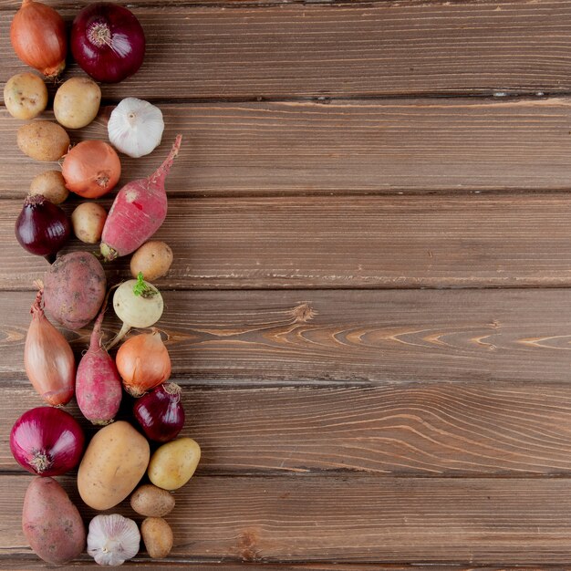 Vertikale Ansicht von Gemüse als Rettich-Zwiebel-Knoblauchkartoffel auf hölzernem Hintergrund mit Kopienraum