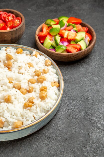 Vertikale Ansicht von gewürzten Erbsen und Reis für Abendessen und Sauerkraut und Salat auf schwarzem Tisch