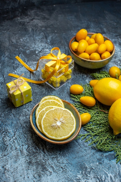 Vertikale Ansicht von halben und ganzen frischen Zitrusfrüchten und gelben Geschenkboxen auf dunklem Hintergrund