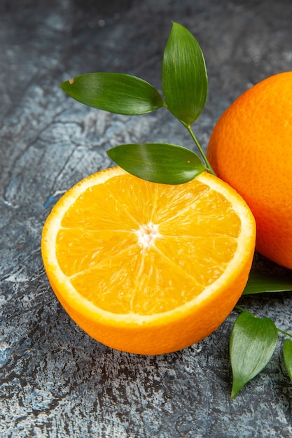 Vertikale Ansicht von halbierten und ganzen frischen Orangen mit Blättern auf grauem Hintergrund stockfoto