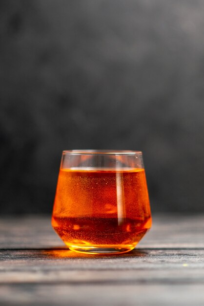 Vertikale Ansicht von köstlichem Orangensaft in einem Glas auf dunklem Hintergrund