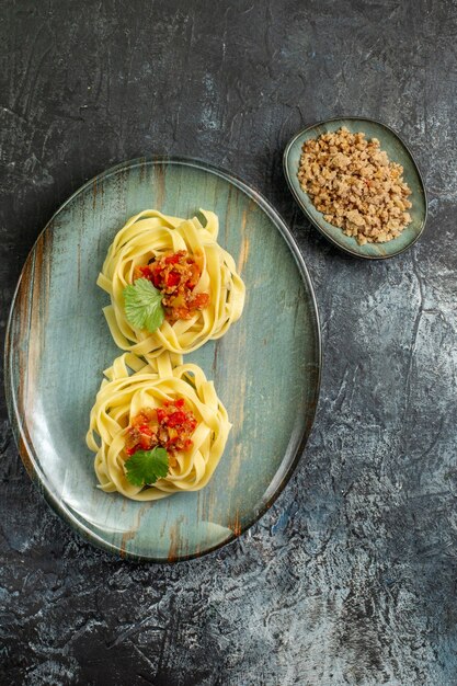 Vertikale Ansicht von köstlichen Pastagerichten mit Tomatenfleisch und Grün auf einem blauen Teller auf Eishintergrund