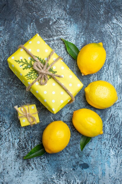 Vertikale Ansicht von organischen natürlichen frischen Zitronen mit Blättern und gelben Geschenkboxen auf dunklem Hintergrund