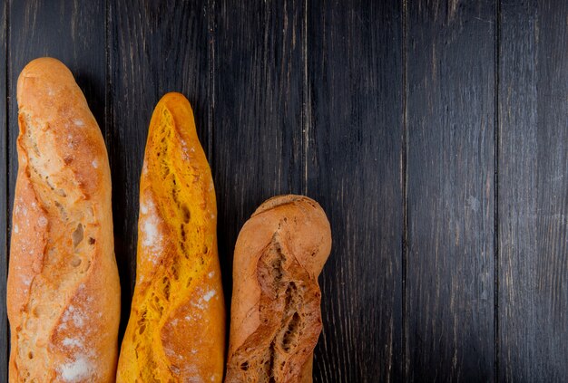 Vertikale Ansicht von verschiedenen Arten von Baguette auf hölzernem Hintergrund mit Kopienraum