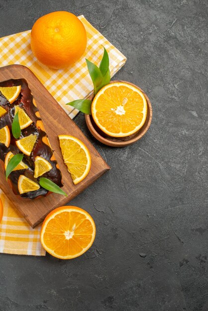 Vertikale Ansicht von weichen Kuchen ganz und geschnittene Zitronen mit Blättern auf dunklem Tisch