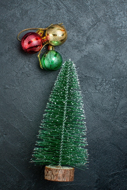 Vertikale Ansicht von Weihnachtsbaum und Dekorationszubehör auf der linken Seite auf schwarzem Hintergrund