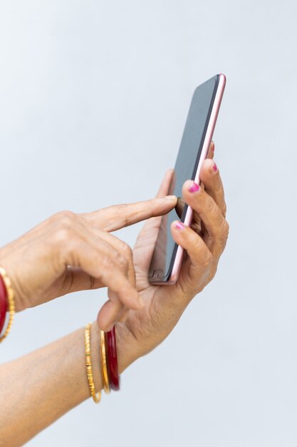 Vertikale Aufnahme der faltigen Hände einer Frau mit einem modernen Smartphone