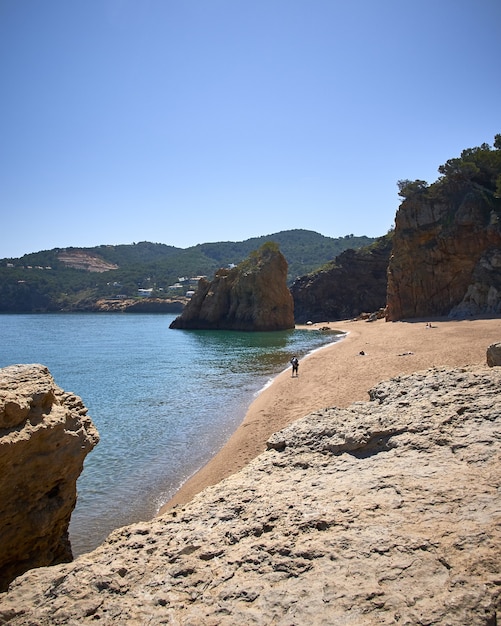 Vertikale Aufnahme der Felsen am Ufer des Meeres am öffentlichen Strand Playa Illa Roja in Spanien