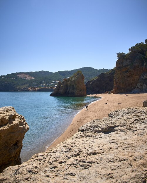 Vertikale Aufnahme der Felsen am Ufer des Meeres am öffentlichen Strand Playa Illa Roja in Spanien