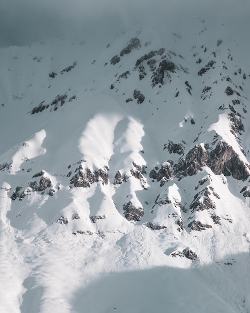 Vertikale Aufnahme der mit Schnee bedeckten felsigen Berge