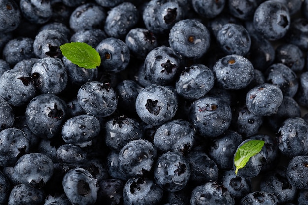 Vertikale Aufnahme der Nahaufnahme von Blaubeeren mit Wassertropfen und Blättern