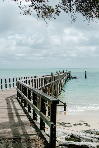 Vertikale Aufnahme der schönen Ansicht des Ozeans mit einem hölzernen Pier an der Küste