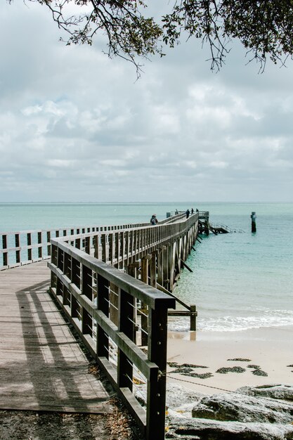 Vertikale Aufnahme der schönen Ansicht des Ozeans mit einem hölzernen Pier an der Küste