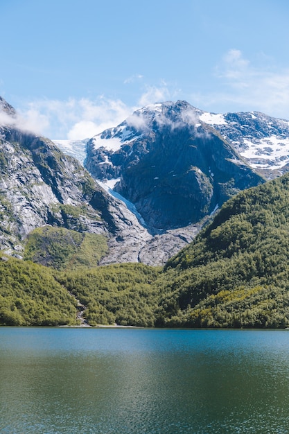 Vertikale Aufnahme der schönen Berge durch den ruhigen Ozean, der in Norwegen gefangen genommen wird