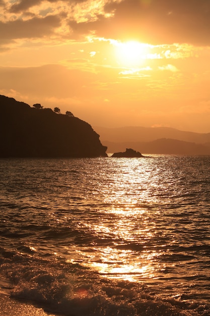 Vertikale Aufnahme des Meeres, umgeben von Bergen während des Sonnenuntergangs