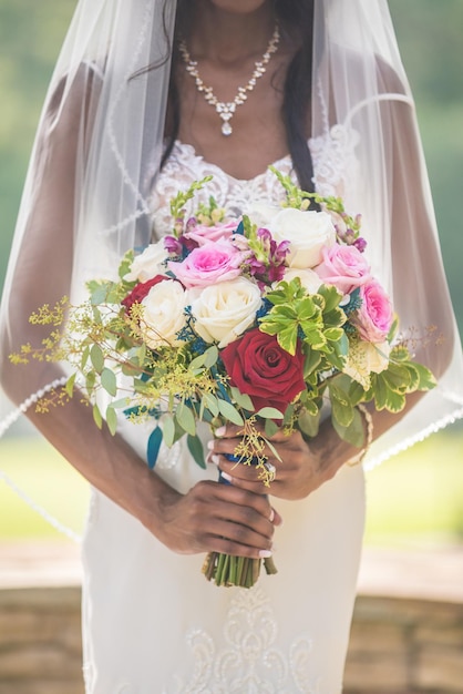 Vertikale Aufnahme einer afroamerikanischen Braut, die den Rosenstrauß hält
