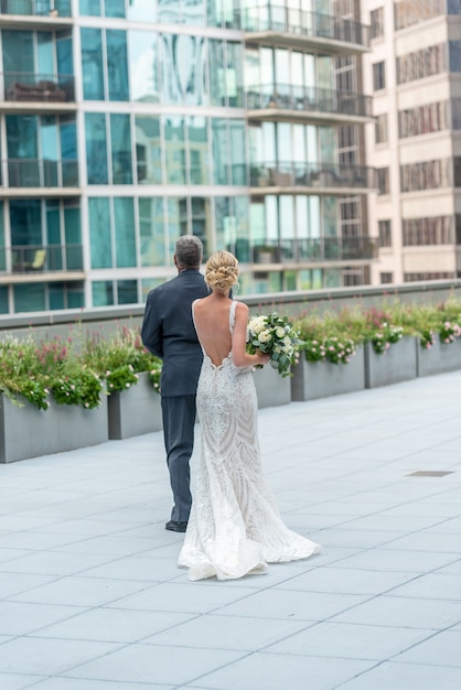 Vertikale Aufnahme einer Braut und eines Bräutigams auf dem schönen Balkon, der die Gebäude betrachtet