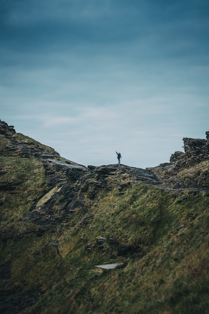 Vertikale Aufnahme einer einsamen Person, die auf einer Klippe steht