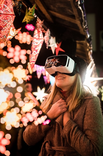 Vertikale Aufnahme einer Frau, die die imaginäre Atmosphäre mit VR-Brille genießt