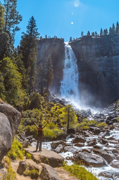 Vertikale Aufnahme einer Frau, die im Wasserfall Vernal Falls des Yosemite-Nationalparks in den USA wandert