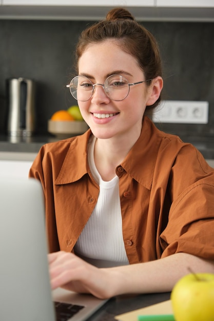 Kostenloses Foto vertikale aufnahme einer frau, die von zu hause aus als unternehmerin arbeitet und mit dem laptop in sozialen medien surft