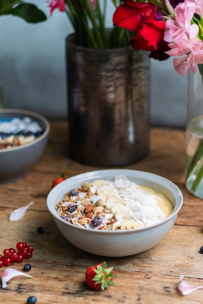 Vertikale Aufnahme einer gesunden Smoothie-Schüssel mit Früchten und Müsli