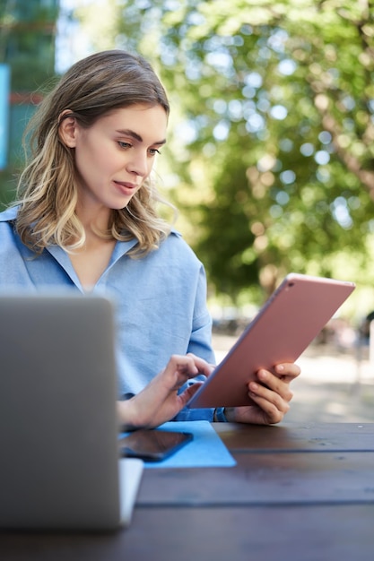 Vertikale Aufnahme einer jungen Studentin, die auf einem digitalen Tablet liest und im Freien studiert Geschäftsfrau sitti