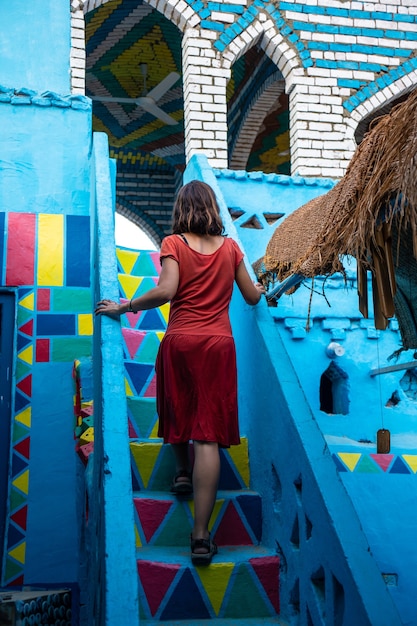 Vertikale Aufnahme einer kaukasischen Frau, die die Treppe im traditionellen blauen Haus erklimmt